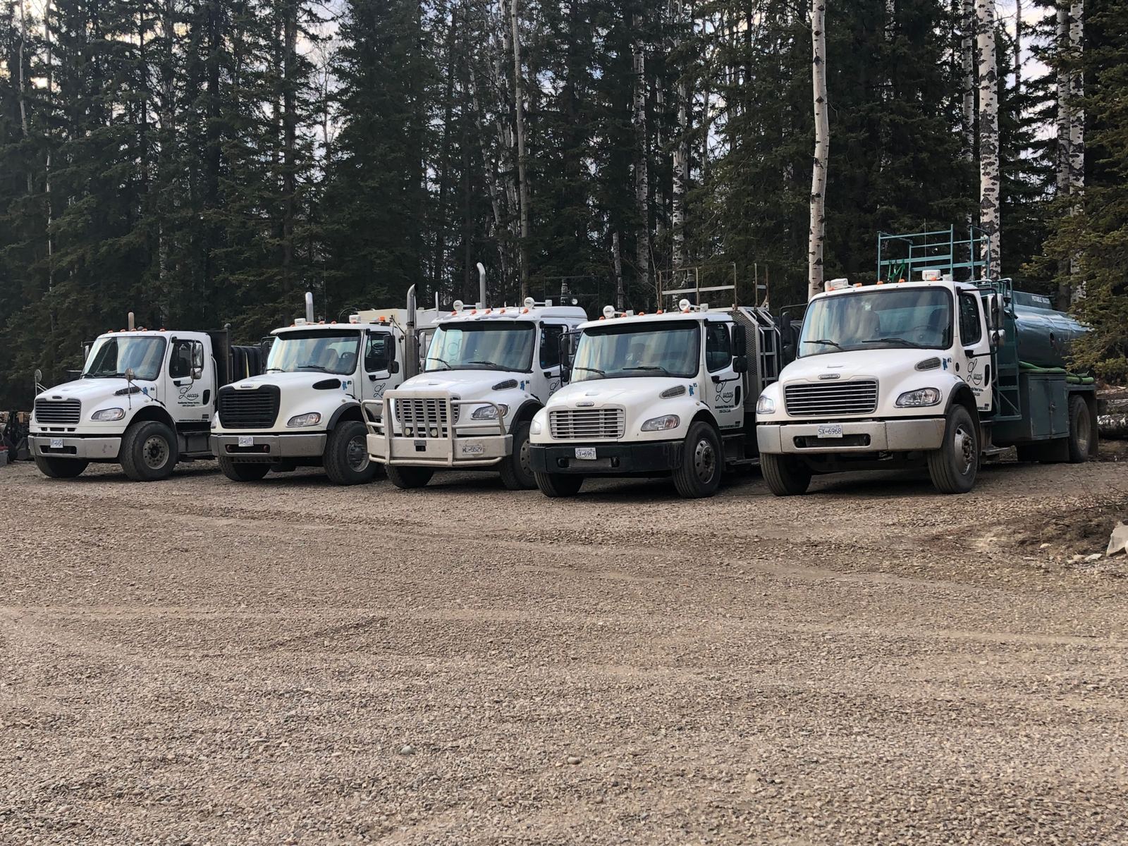 Five Lucas Water trucks lined up in a gravel yard